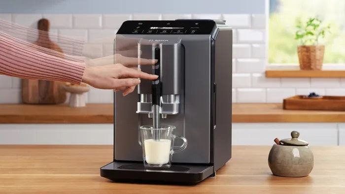 Sleek coffee machine on a kitchen counter with a person using it.