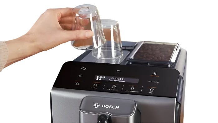 Bosch coffee machine with a hand holding a clear glass container on a kitchen counter.